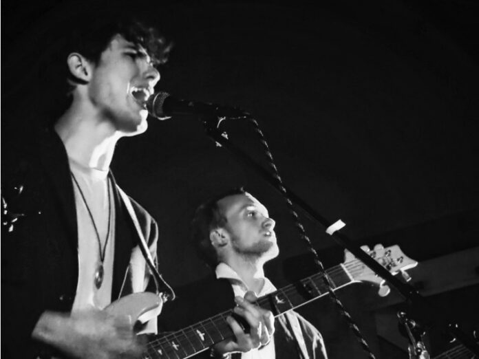 a-band-of-friends-3-minutes-late-1 Three guitarists performing with electric guitars on stage during UD's Battle of the Bands.