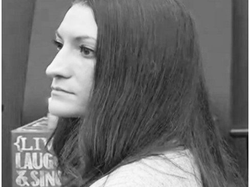 A person from behind with dark hair wearing striped clothing.