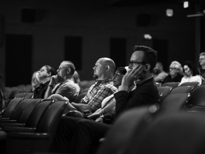 juvie-kids-learn-shakespeare-with-lemieux-1 Black and white photo of audience members seated in an auditorium, watching a theatrical performance.