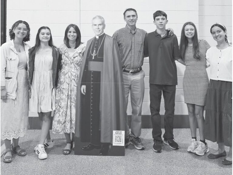 A family group with a cardboard cutout of Fulton Sheen at his beatification
