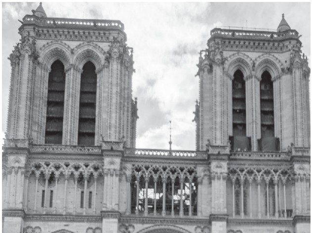 the-paradox-of-catholicism-in-france-1 Ornate stone facade of a Gothic cathedral with a large rose window and arched doorways.