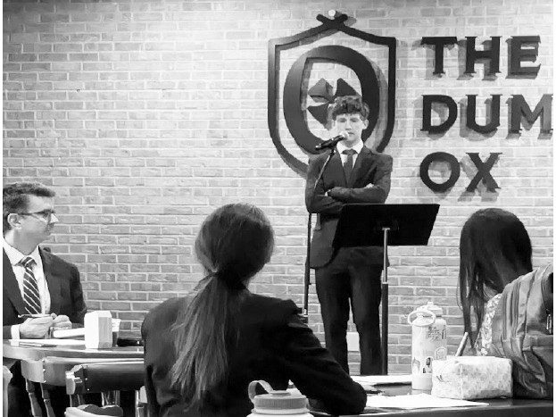 ud-civic-fellows-debut-with-debate-on-praise-and-worship-music-1 People participate in a debate event, with a speaker at a podium and audience members seated at a table.